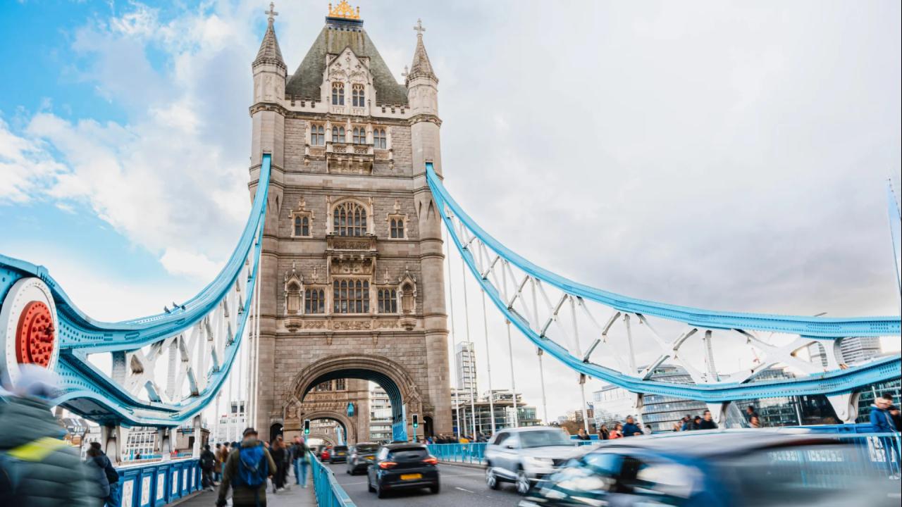 Vehicles and people going across Tower Bridge in London