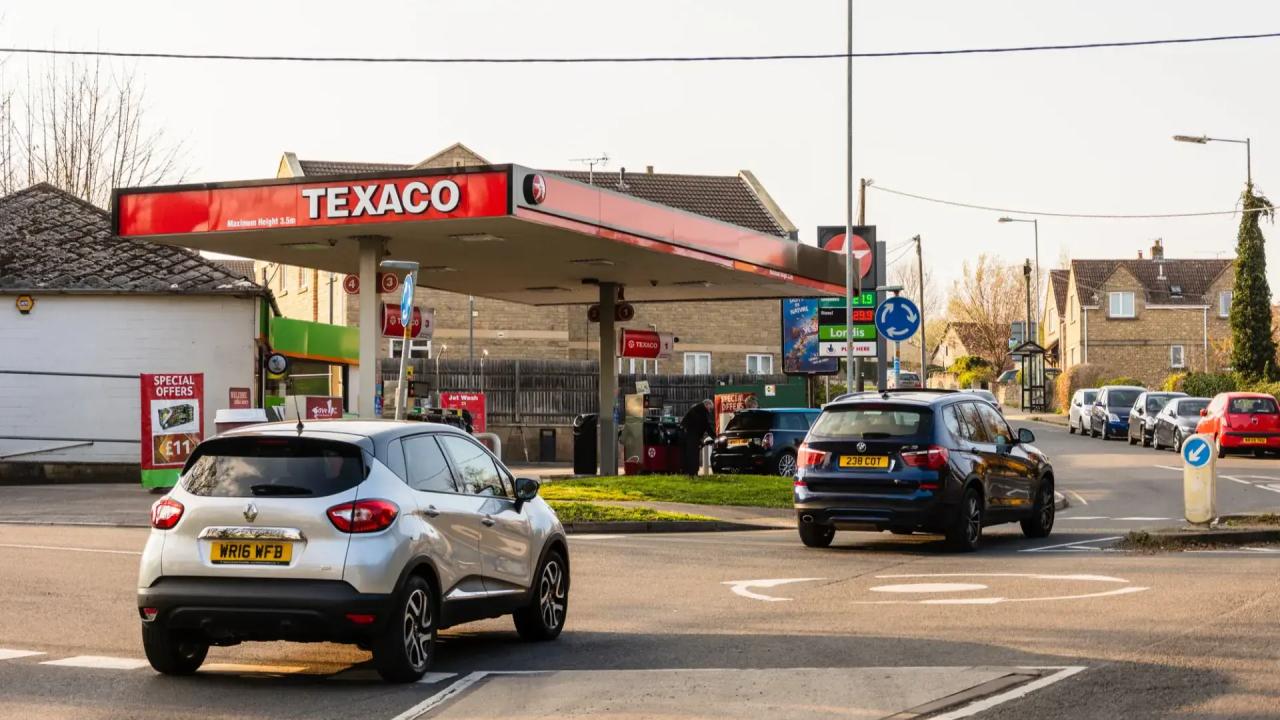 Cars driving past a Texaco petrol station in a small rural village